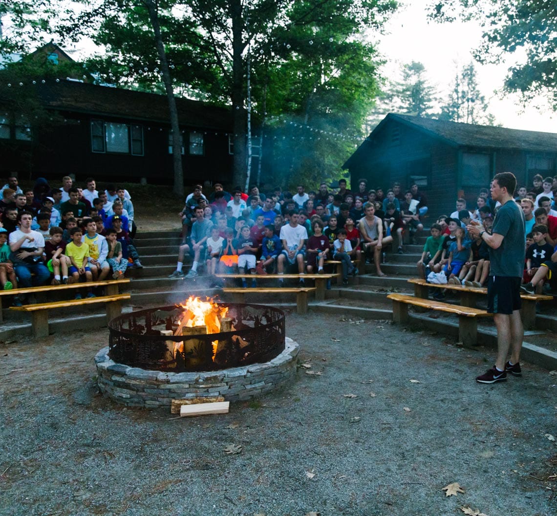 Campfire and campers sitting on bleachers