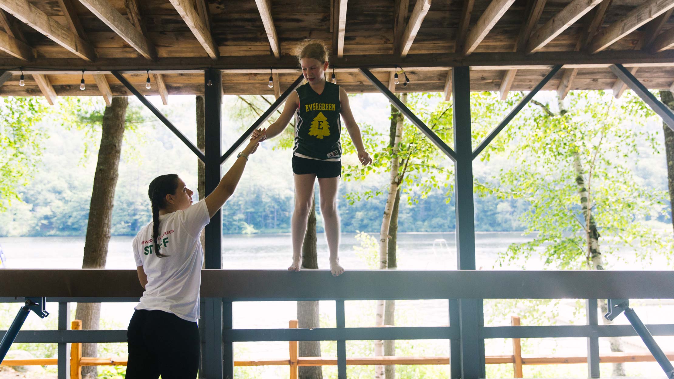 Gymnastics instructor helping camper on balance beam