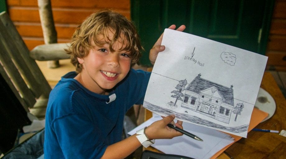 Boy showing off drawing of camp