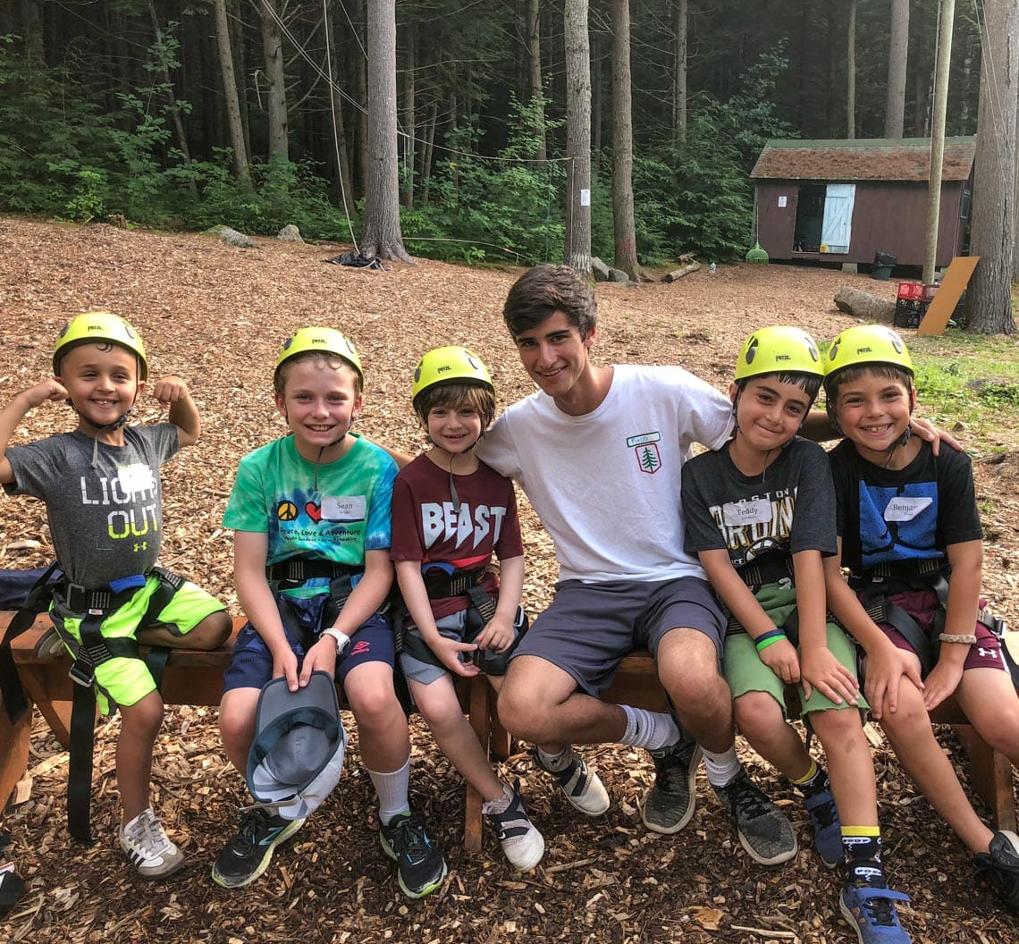 Boys with helmets and climbing harnesses sitting